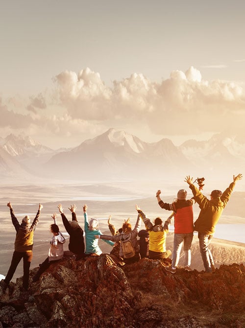 A group of travelers greet the sunrise on a mountain top far away.