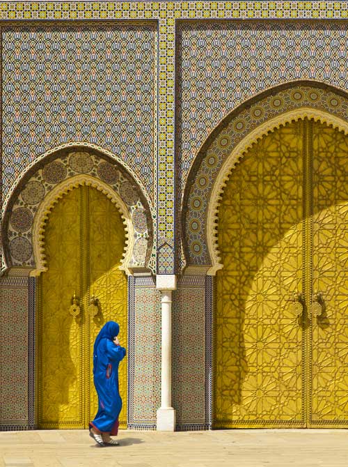 Woman in blue walking in front of mosque with yellow doors - international health
