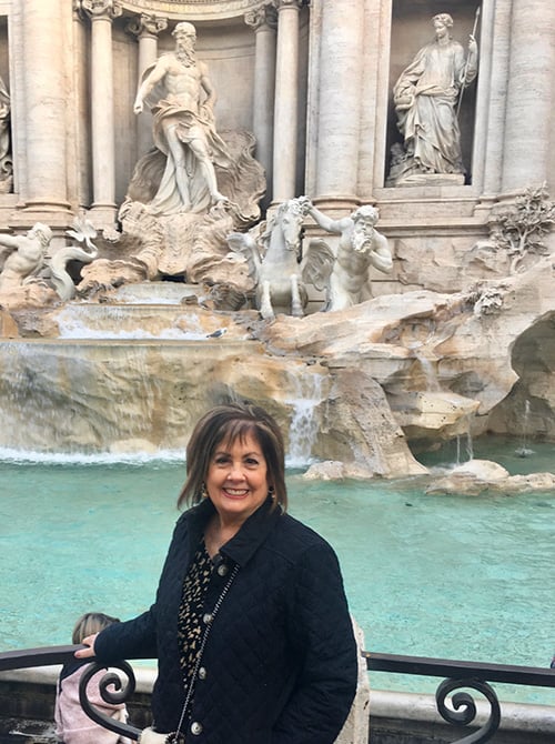 Provident Travel advisor Janet McLaughlin standing at fountain entrance to La Canonica di Cortine, Rome, Italy
