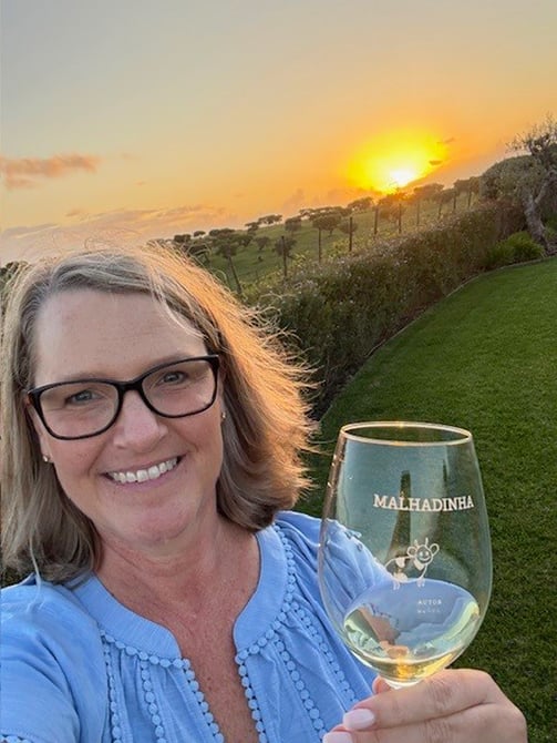 Provident Travel Advisor Lori O'Connor enjoying wine in vineyard at sunset in Alentejo, Portugal