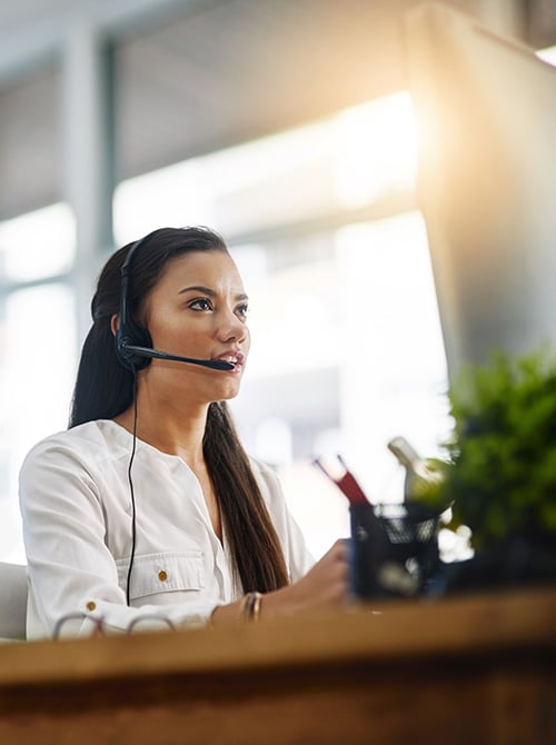 Travel advisor wearing a headset assisting a client over the phone from an office.