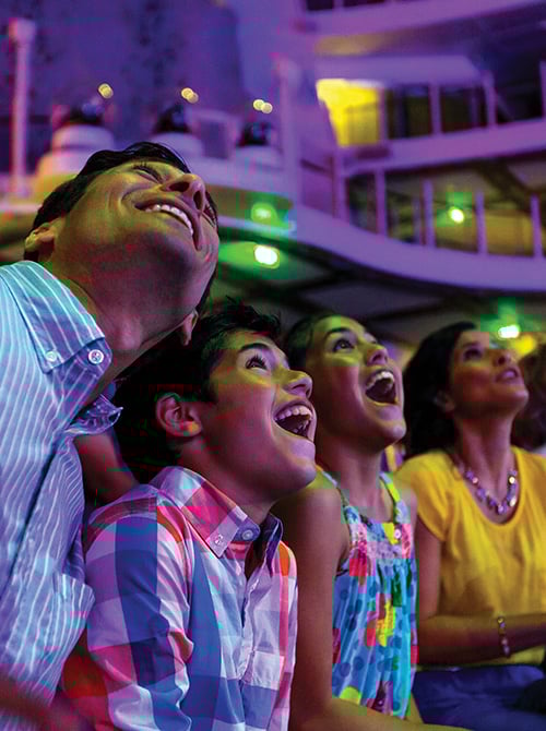 Family watching a show on a cruise ship, looking upwards with excitement
