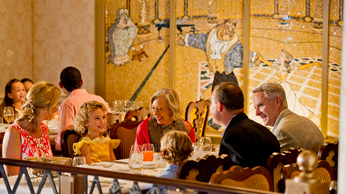 Family dining at an elegantly decorated restaurant on a cruise ship with a fairytale-themed mural in the background
