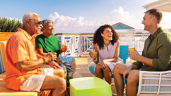Two couples chatting on a cruise patio deck and enjoying beverages