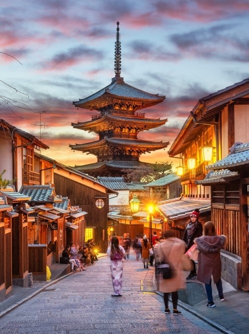 Tourists standing on street at sunset in front of a pagoda