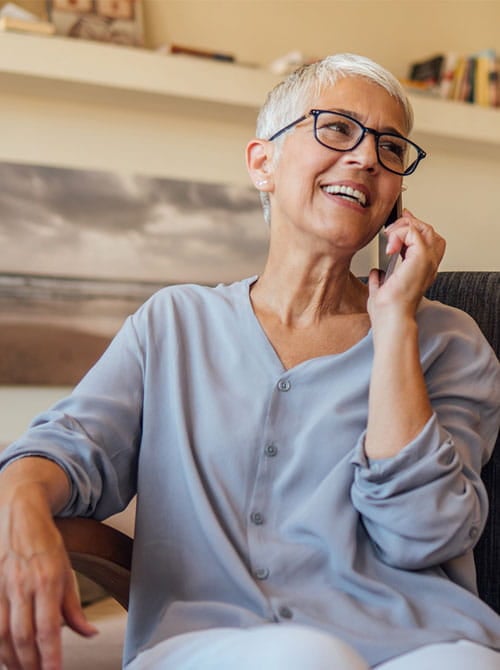 Woman with silver hair holding smartphone to her ear and smiling