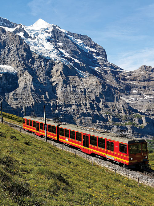 A red train traveling through the mountainside in Switzerland