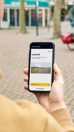 Mobile phone in hand displaying AA Driving School App