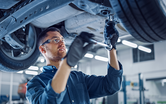 A mechanic looking underneath a car