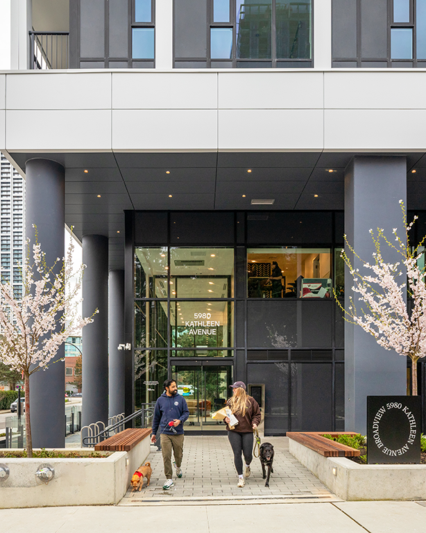 2 people in front of building with dogs