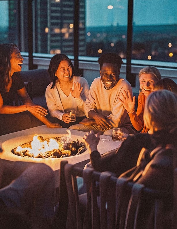 Friends laughing around a rooftop firepit