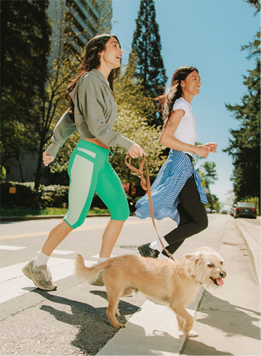 2 girls crossing the street with a dog