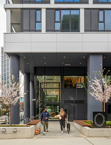 Two people walking with dogs outside a building