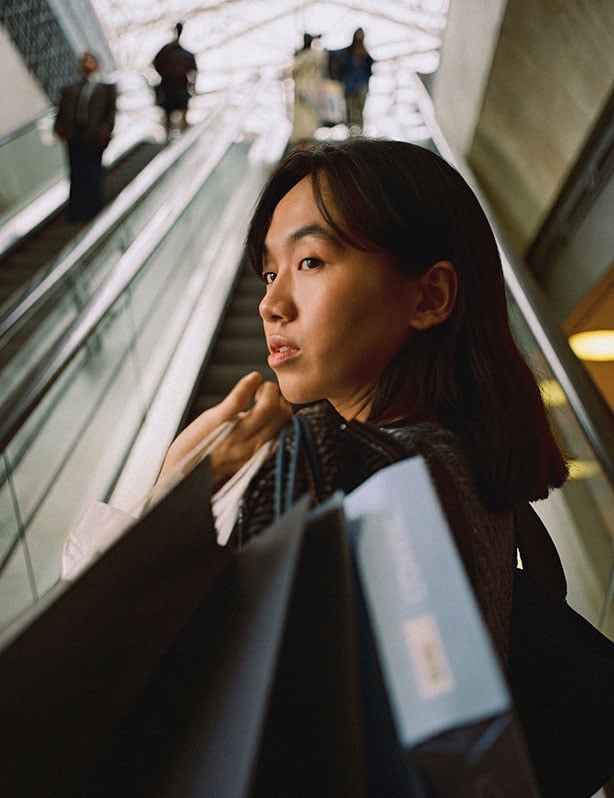 Woman on escalator with shopping bags
