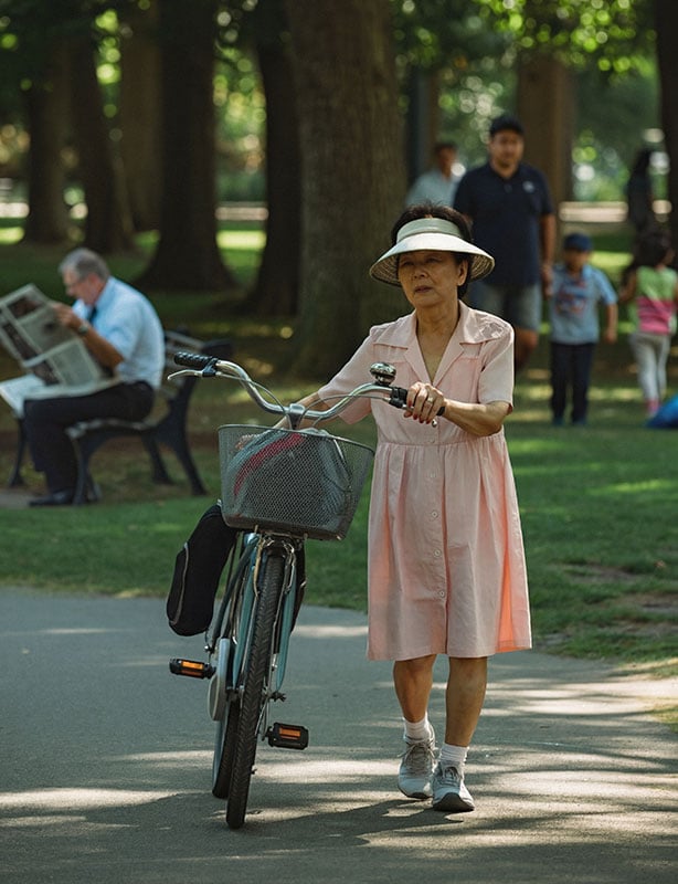 Woman wearing a pink dress walking a bike