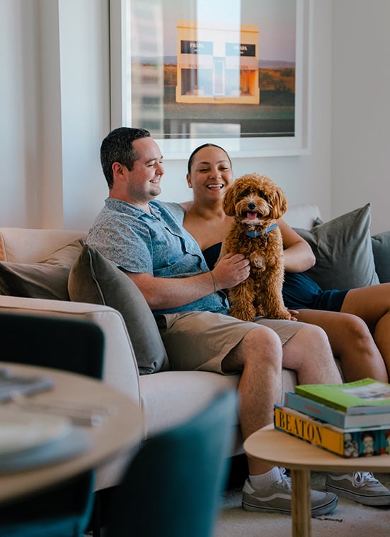 Couple sitting on a sofa with a dog in their living room