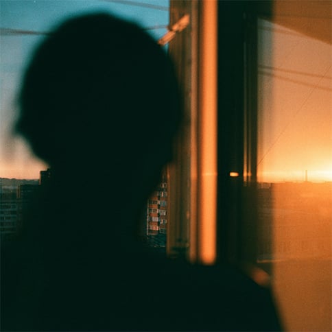 Person standing in the shadows watching the sunset