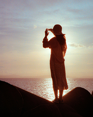 Woman overlooking the ocean and sunset