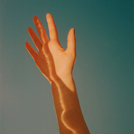 Hand reaching towards the sky with sunlight