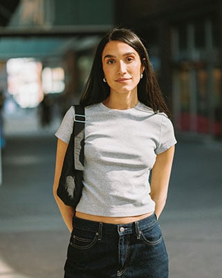 Portrait of a woman in a grey shirt holding a bag