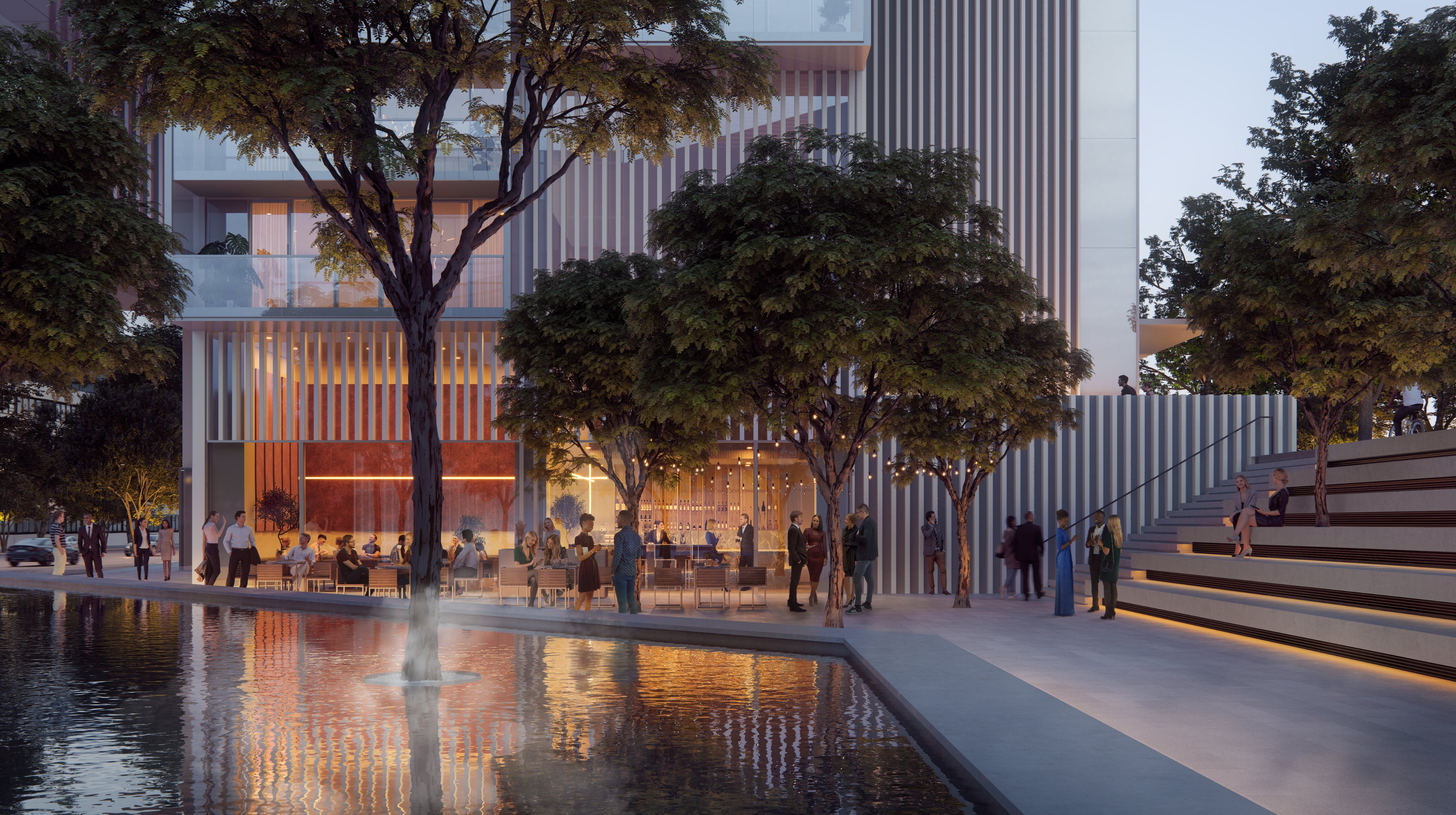 People socializing on the ground floor of Fifteen Fifteen around a fountain surrounded by greenery