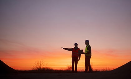 Two construction workers at sunset