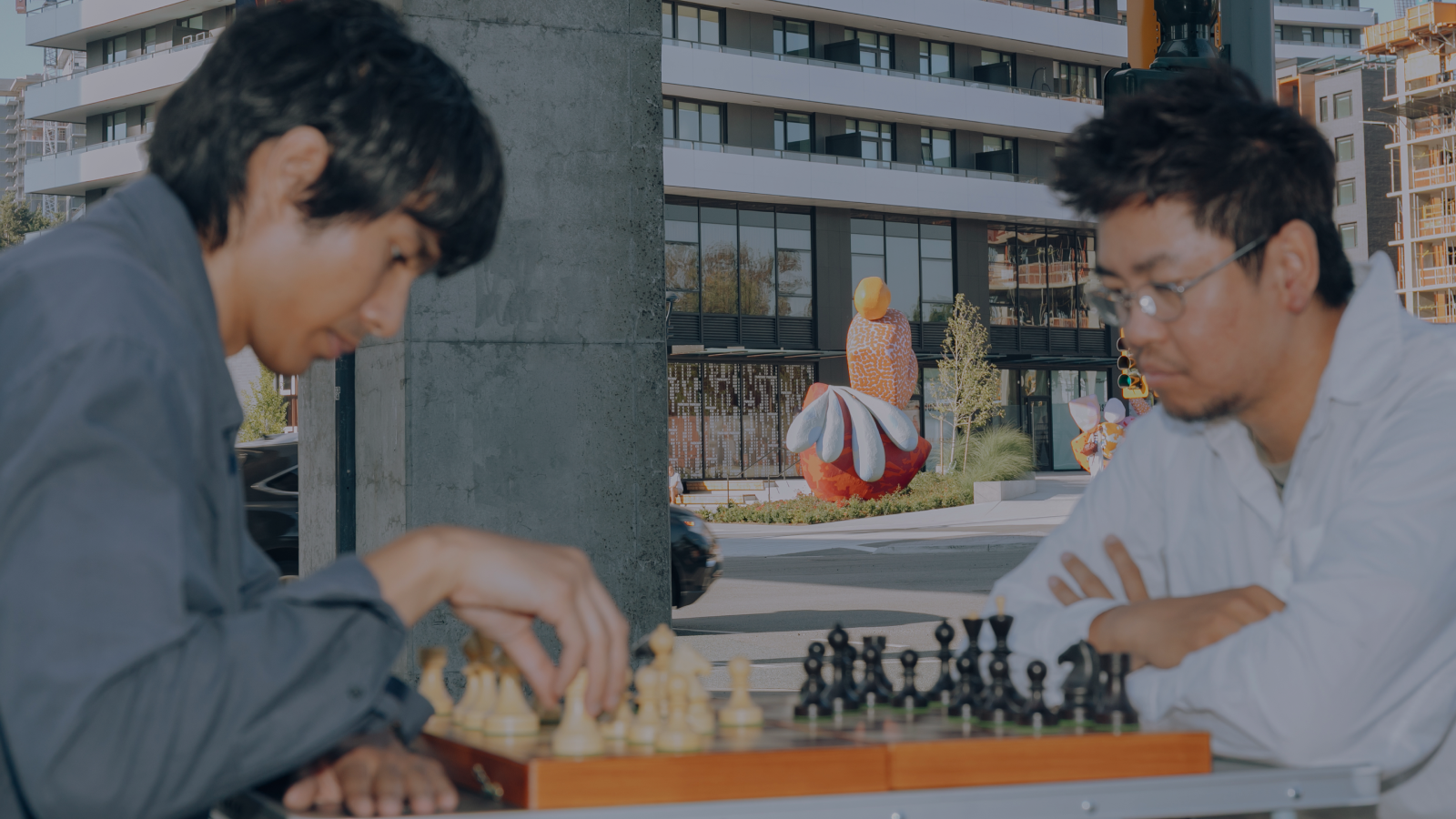A man playing chess in front of PKWY public art