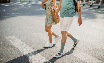 People crossing crosswalk with sun shining on the pavement