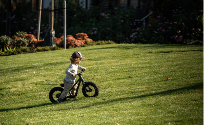 Child riding a bike on a grassy field