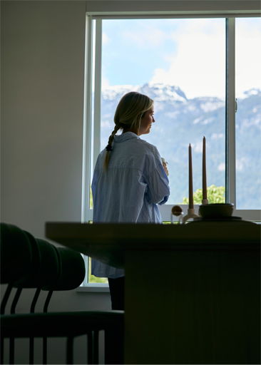 Woman looking out a window at mountains
