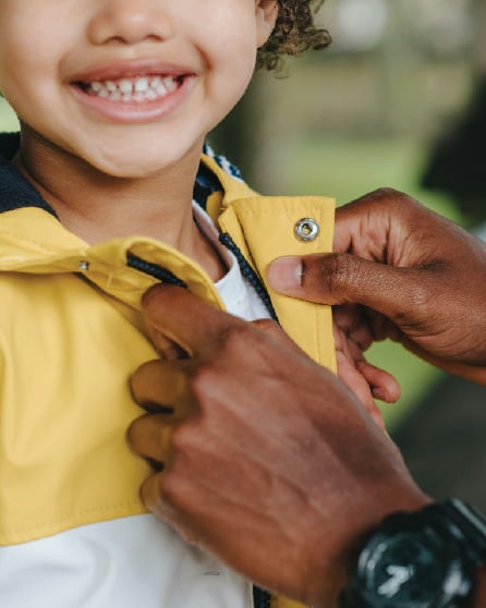 child getting jacket zipped up smiling