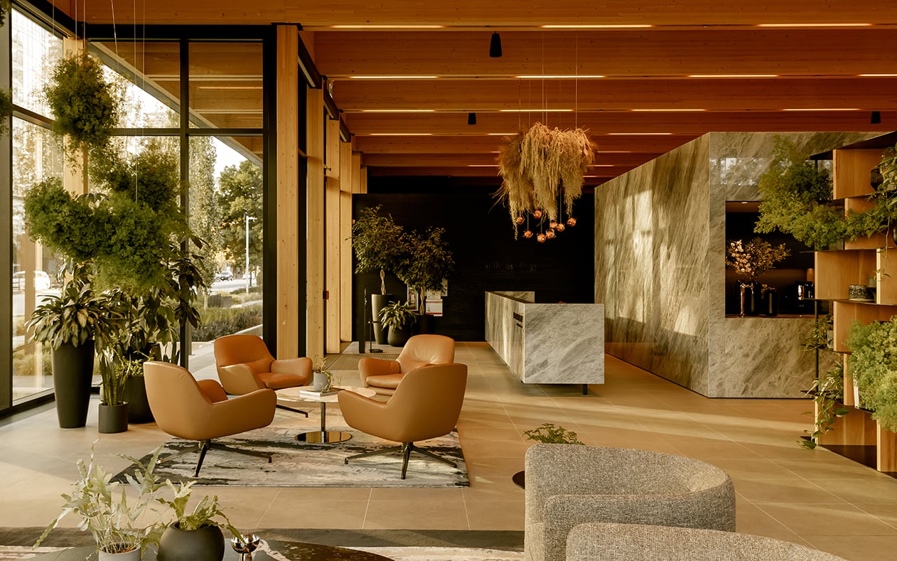 Inside a sales gallery adorned with light coloured wood and bathed in sunlight and greenery