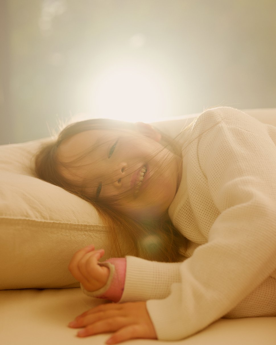 Child laying on a pillow with sunlight behind