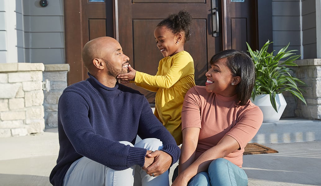 Trust fire safety protection. A family of three sit outside their home.