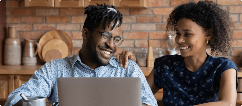 Smiling couple looking at laptop together. 