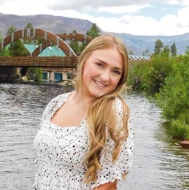 a woman standing in front of a river and a bridge