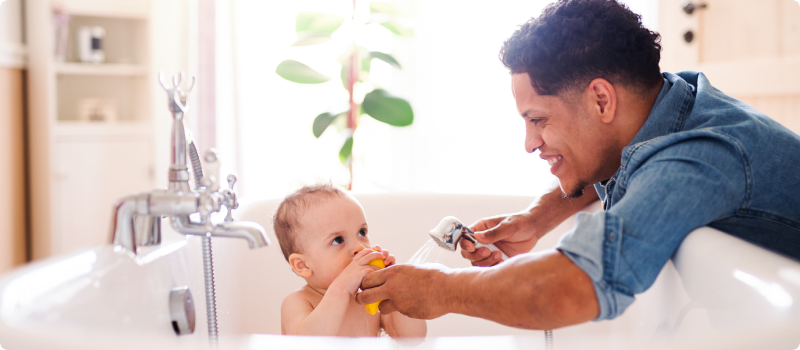 Father washing a toddler in a bath tub