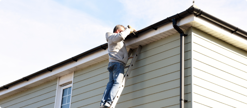 a man attaching gutters to a house