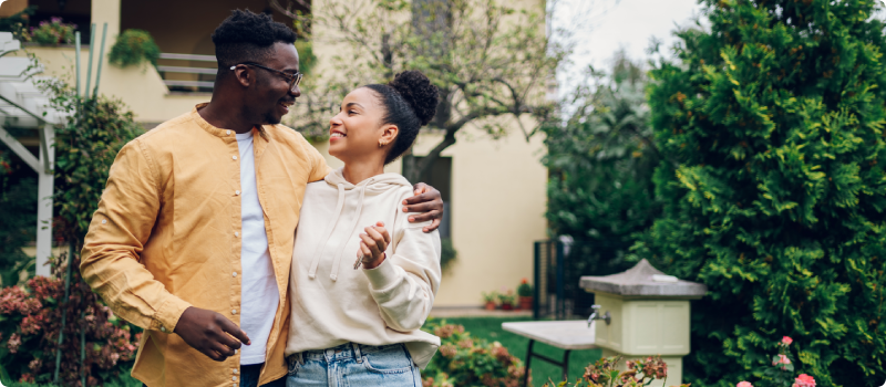 a couple embracing outside their home