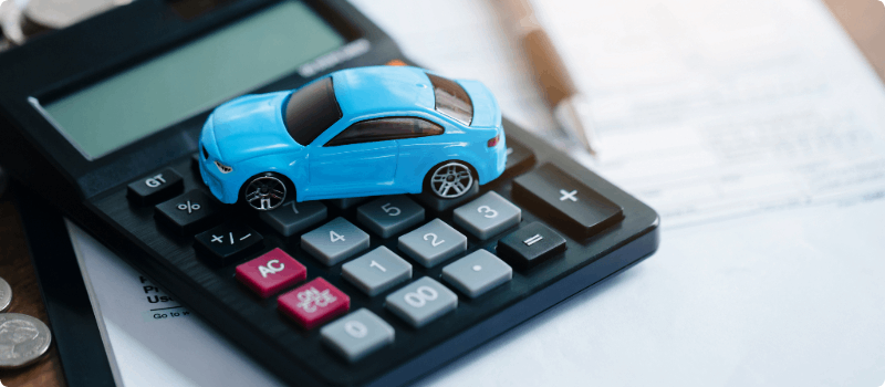 A toy car sitting on top of a calculator.
