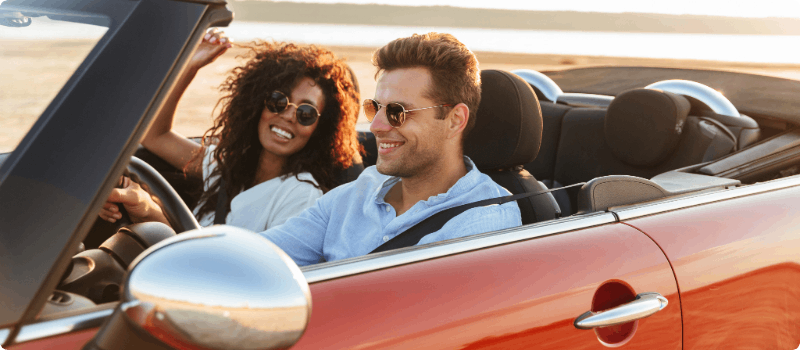 Two people going for a drive in a convertible on a sunny day.