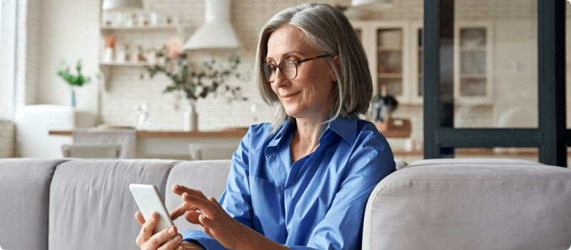 A person sitting on her living room couch while looking at her phone.