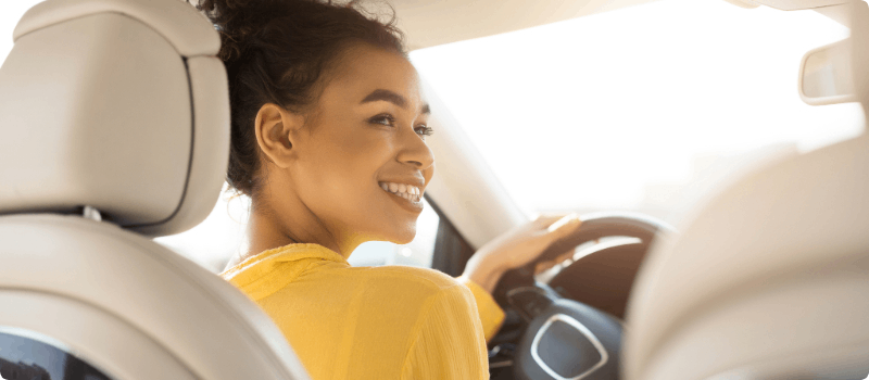 A young person sitting behind the wheel of a car. 