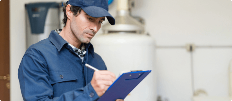 A worker inspecting a home water heater.