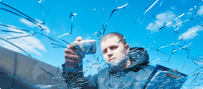 Person taking a photo of a broken windshield.