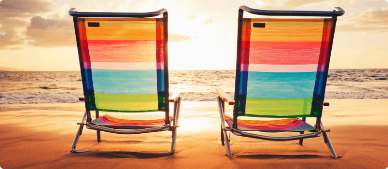 Two beach chairs on a beach.