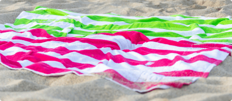 Towels laying on a sandy beach. 