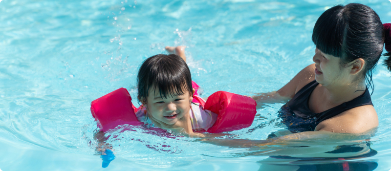 A close-up of a parent teaching their child to swim.