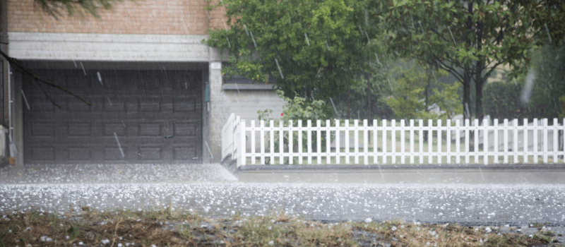 Home with fence during a hailstorm. 