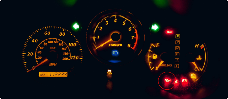 A close-up of a check oil light illuminated on a car's dashboard light.